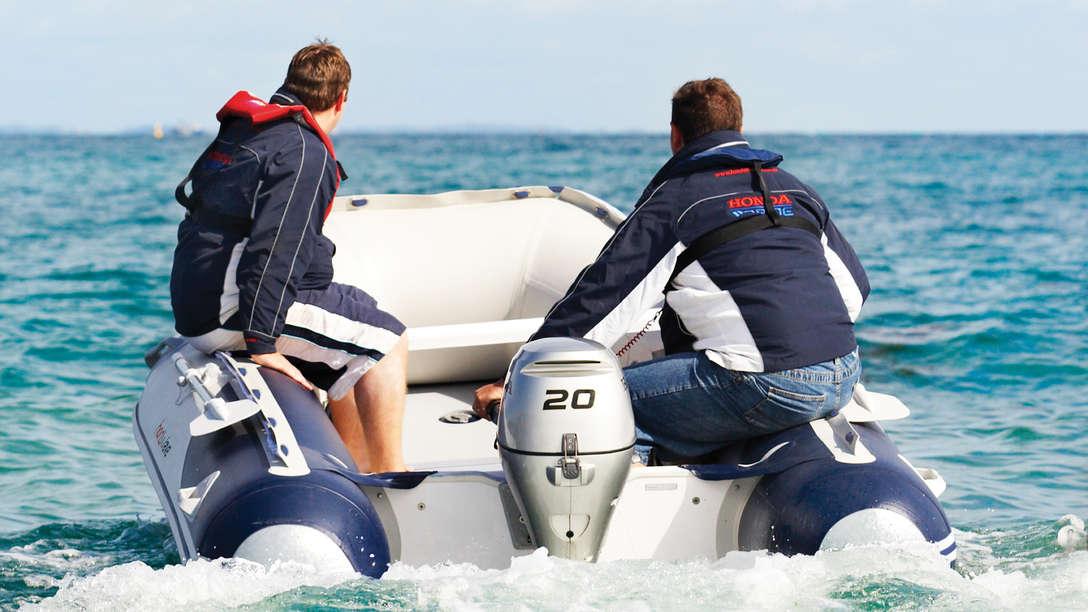 Dos amigos navegando con embarcación neumática Honwave equipada con un motor fueraborda Honda